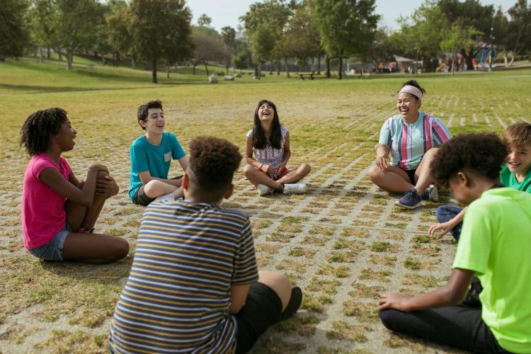 group of children sitting in a circle outside in the grass 