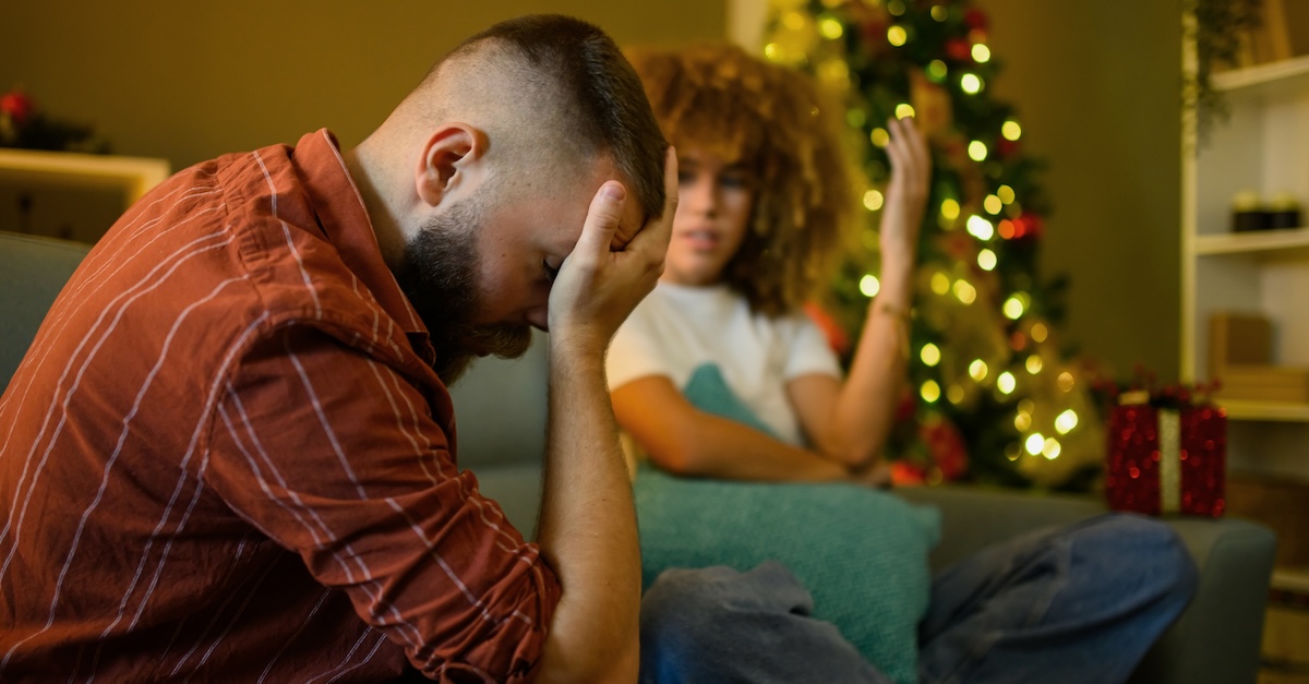 Married couple arguing at Christmas by tree on couch holidays